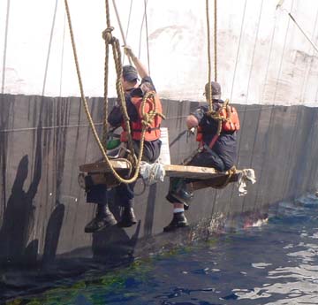 staging: cadets hang over the side to paint the hull while anchored in the Caymans.