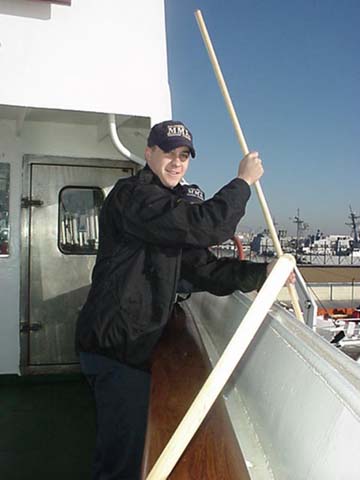 deck maintenance: 3/c Kyle Higginbottom (Taunton,MA) tends to the outside of the ship