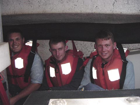 lifeboat drill: cadets wait in the covered lifeboat for the drill to start