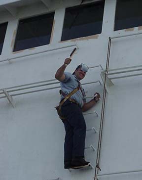 housepaint: 1/c Alejandro Pinzon (Panama City, Panama) wire brushes the forward portion of the house in preparation for painting.