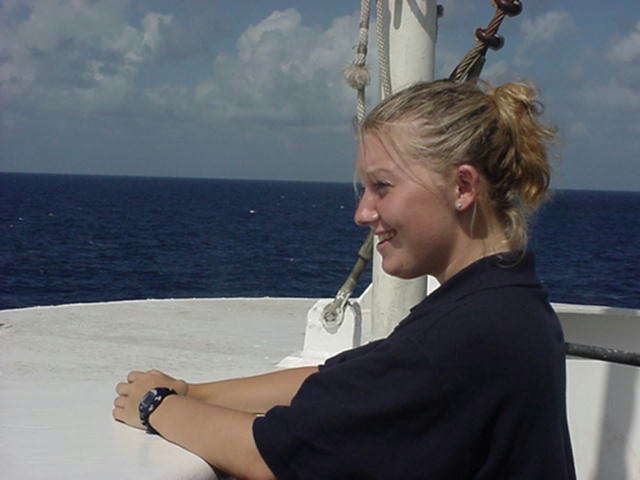Atbow.jpg: 3/c Erin Derito from Brockton,MA keeps a look out on the bow. A nice job in the sunny southlands... next week she won't be smiling when the ship passes Cape Hatteras.
