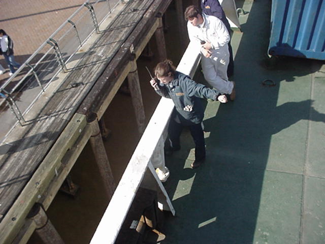 NOLA docking 3.jpg: 1/c Eunice Cadorette gives the "hold" signal to the winchman as the Empire State ties up to the wharf in NOLA. Capt Luke Catarius looks on.