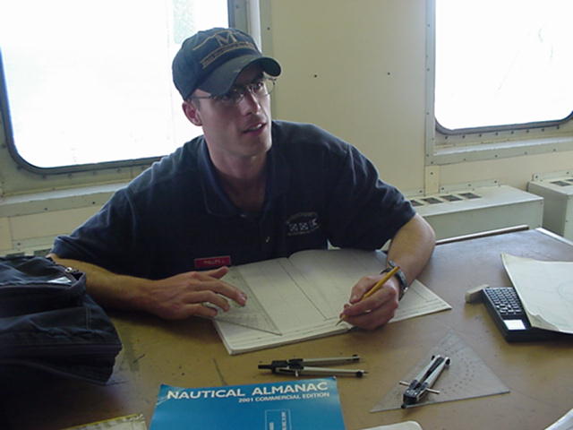 Philips.jpg: Cadet Chief Mate Justin Phillips works on his navigation logs in the after chartroom. Dropping the anchor takes a lot of paper work.